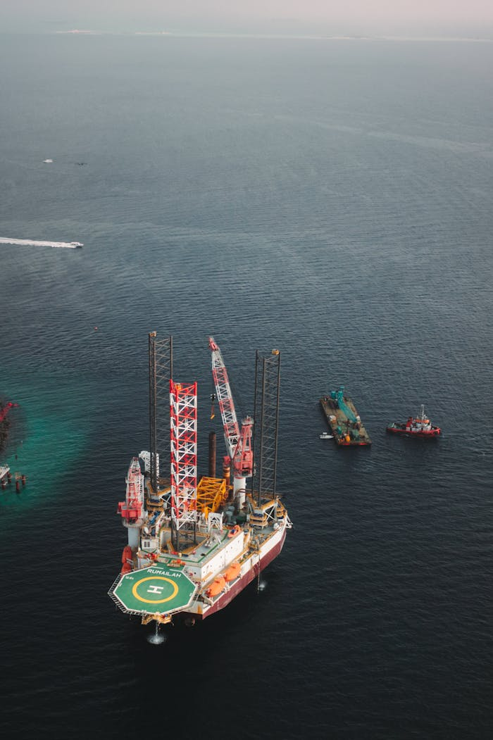 Aerial shot of an offshore oil platform with ships in a calm sea.